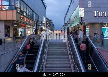 Suzhou, China - 11. Juni 2024 : Menschen gehen auf einer Rolltreppe und Treppen in der Nähe eines Einkaufszentrums in der Stadt Suzhou, China. Stockfoto