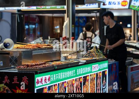 Suzhou, China - 11. Juni 2024 : Ein Straßenhändler in Suzhou, China, verkauft Fleischspieße und Gemüse. Stockfoto