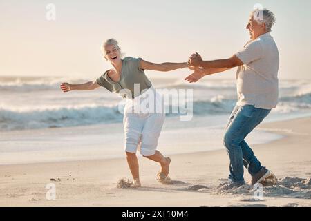 Altes Paar, das Hände hält und am Strand um Liebe, Reisen und Meereswellen für den Ruhestand spielt. Senioren, Ehe und Urlaub zum Lachen Stockfoto