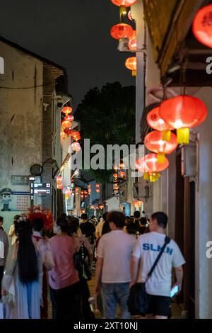 Suzhou, China - 11. Juni 2024 : Eine überfüllte Straße in Suzhou, China, gesäumt von roten Laternen und Gebäuden in der Nacht. Stockfoto