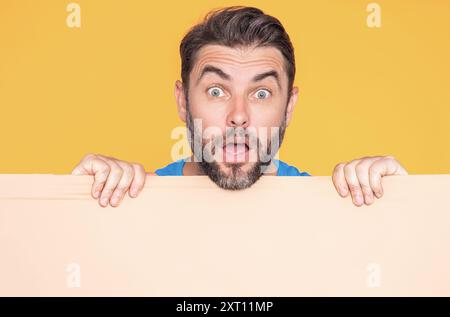 Informationskonzept. Überraschter Mann mit leerem Schild. Demonstrieren des Kopierraums für Text oder Design. Staunender, aufgeregter Mann mit leerer Werbung Stockfoto