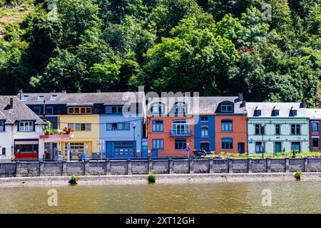 Farbenfrohe Gebäude entlang der Maas im Stadtbild des Ferienortes Dinant, üppige Bäume auf dem Hügel im Hintergrund, sonniger Sommertag in der Provinz Namu Stockfoto