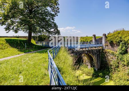 Fußgängerweg, der zur Brücke in der Festung Charlemont führt, Graben mit stehendem Wasser mit blühenden Algen, Ziegelmauern, sonniger Sommertag mit blauem Himmel i Stockfoto