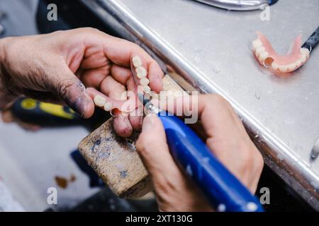 Von oben abgeschnittene, nicht erkennbare Nahaufnahme der Hände eines Profis, die in einem Dentallabor akribisch Prothesen herstellen und Formen. Stockfoto