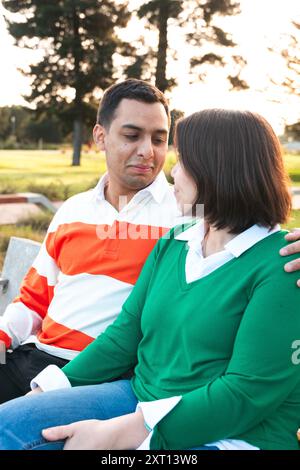 Ein junges Latino-Paar teilt eine sanfte Umarmung und vermittelt Wärme und Zuneigung in einer ruhigen Umgebung im Freien, wenn die Sonne untergeht Stockfoto