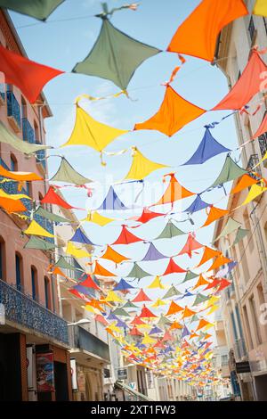 Farbenfrohe Regenschirme, die über einer sonnigen Straße hängen, schaffen eine festliche und skurrile Atmosphäre. Bola02482 Copyright: XConnectxImagesx Stockfoto