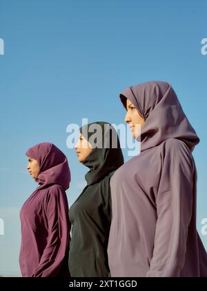 Drei Frauen in Hijabs stehen im Profil vor einem klaren blauen Himmel. Bola02590 Copyright: XConnectxImagesx Stockfoto