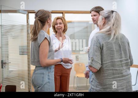 Vielfältige Situation in een huisartsenpraktijk Gruppe von vier Erwachsenen, die sich in einem hellen Bürobereich in zwangloser Atmosphäre unterhalten. Molenhoek Nederland DEL Stockfoto