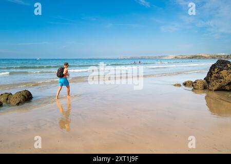 Ein Urlauber, der einen Spaziergang entlang der Küste am Towan Beach in Newquay in Cornwall in Großbritannien macht. Stockfoto