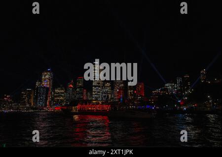 Ein beleuchteter Passagierkreuzer mit einem roten Lichtschild mit den Worten Vividsydney segelt vor dem Central Business District (CBD) von Circ Stockfoto