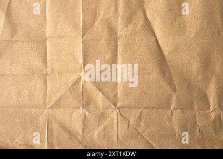 Braunes altes zerknittertes Blatt Papier mit geraden geometrischen Falten und Falten, die ein natürliches Schmirgelmuster bilden. Abstrakter grober Hintergrund Stockfoto