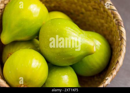 Grüne frisch gepflückte saftige Feigen in einer umweltfreundlichen Korbschale aus nächster Nähe. Fruchterntekonzept Stockfoto