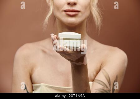 Eine junge Frau mit Vitiligo hält ein Cremeglas vor sich und zeigt ihre Schönheit und ihr Selbstvertrauen. Stockfoto