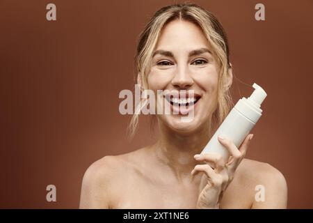 Eine junge Frau mit Vitiligo lächelt hell, während sie ein Hautpflegeprodukt hält. Stockfoto