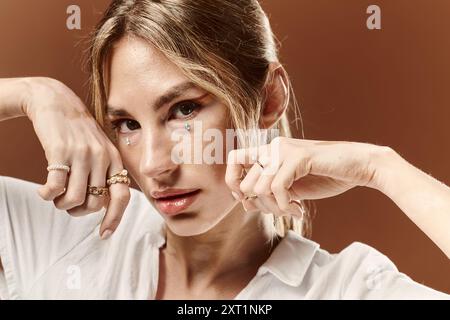 Eine junge Frau mit Vitiligo posiert selbstbewusst in einem weißen Sommeroutfit und zeigt ihre einzigartige Schönheit vor beigefarbenem Hintergrund. Stockfoto