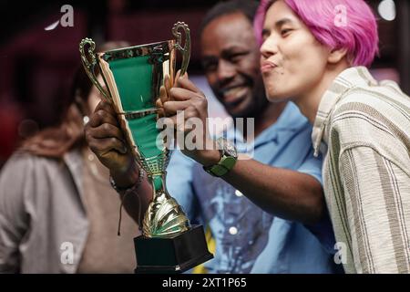 Eine Gruppe von Freunden lächelt und hält stolz die Trophäe zusammen. Ausdrucksformen der Freude und Kameradschaft, die perfekt in Momenten der Leistung mit verschiedenen Freunden aufgenommen wurden Stockfoto