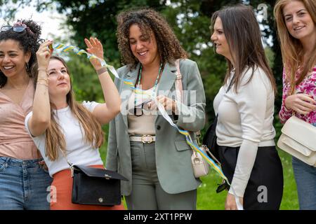 Eine Gruppe von fünf Frauen genießt die gemeinsame Zeit im Freien, lacht und teilt einen verspielten Moment mit bunten Streamern. Panc05458 Copyright: XConnectxImag Stockfoto