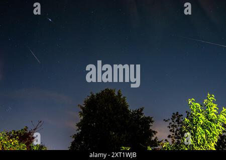 London, Großbritannien. August 2024. UK Weather – Ein zusammengesetztes Bild, das drei Meteoriten des Perseidenschauer in den frühen Morgenstunden in der Nähe von Watford im Nordwesten Londons zeigt. Der Perseiden-Meteoritenschauer ist das Ergebnis einer Staubwolke, die hinter dem Kometen Swift-Tuttle zurückgelassen wurde. Oben rechts ist die schwache Aurora Borealis (Polarlichter) zu sehen, die durch energiereiche Partikel der Sonne verursacht wird, die mit Geschwindigkeiten von bis zu 45 Millionen mph auf die obere Erdatmosphäre treffen. Quelle: Stephen Chung / Alamy Live News Stockfoto