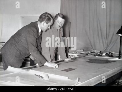 Das Foto zeigt Adolf Hitler zusammen mit seinem Architekten Albert Speer, der Pläne für die Neugestaltung Berlins überprüft. Speer, eine Schlüsselfigur des NS-Regimes, hatte die Aufgabe, Berlin in die Welthauptstadt Germania zu verwandeln, was die Größe und Macht des Dritten Reiches widerspiegelte. Diese Pläne waren Teil der umfassenderen Vision der NS-Führung, die kulturelle und architektonische Landschaft Deutschlands neu zu gestalten, um sie an ihre ideologischen Ziele anzupassen. Stockfoto