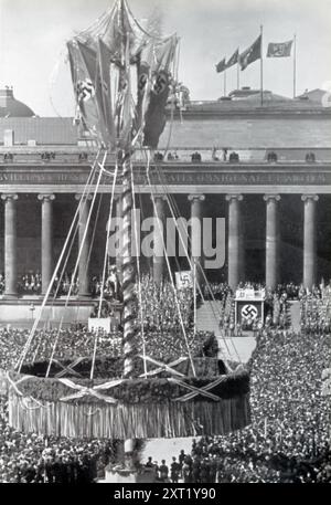 Ein Foto zeigt Adolf Hitler, der am 1. Mai im Berliner Lustgarten mit deutschen Arbeitern spricht. Diese Veranstaltung, bekannt als der Tag der Nationalen Arbeit, war Teil der Bemühungen des NS-Regimes, deutsche Arbeiter zu vereinen und die NS-Ideologie zu fördern. Millionen von Deutschen, darunter Intellektuelle und Arbeiter, versammelten sich, um Hitlers Rede zu hören. Stockfoto