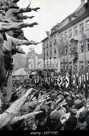 Das Foto zeigt die Kundgebung der Nazi-Partei 1933, bekannt als „Sieg des Glaubens“. Braune Kolumnen der SA (Sturmabteilung), die eine Schlüsselrolle bei Hitlers Aufstieg an der Macht spielten, werden gesehen, wie sie an Hitler vorbeimarschierten, um Loyalität und Triumph zu zeigen. Diese Kundgebung war eine der ersten Großveranstaltungen der Nazis, nachdem sie die Kontrolle über Deutschland übernommen hatten, und symbolisierte die Festigung ihrer Macht und den Beginn ihres totalitären Regimes. Stockfoto