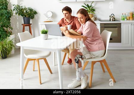 Eine Frau mit einer Beinprothese sitzt mit ihrem Freund an einem Tisch, beide konzentrieren sich auf eine Aufgabe. Stockfoto