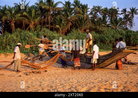 Fischer stehen neben traditionellen Holzfischbooten, die Fischernetze am Induruwa Beach in der Nähe von Bentota, Südprovinz, Sri Lanka sortieren. Archivbild, das 2001 aufgenommen wurde Stockfoto