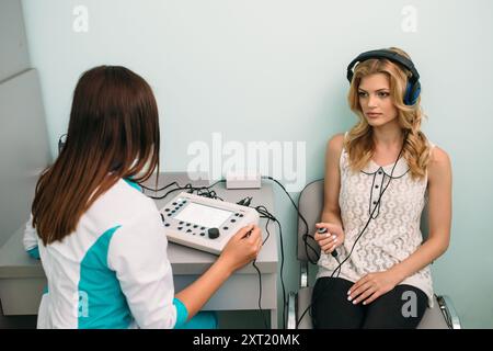 Ein medizinisches Fachpersonal führt einen Hörtest an einen Patienten in einer klinischen Umgebung mit spezialisierten Audiometrie-Geräten durch. Stockfoto