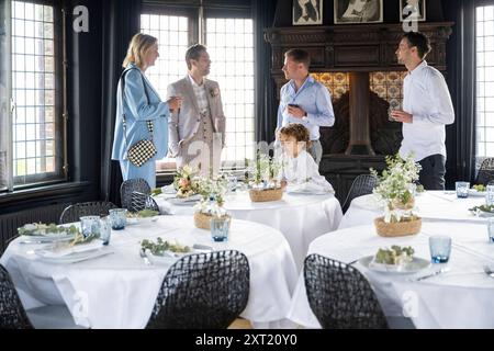 Elegantes Ambiente im Speisesaal mit gut gekleideten Gästen, die Gespräche führen, und einem Tisch mit weißen Blumenmustern. Panc05811 Kopie Stockfoto