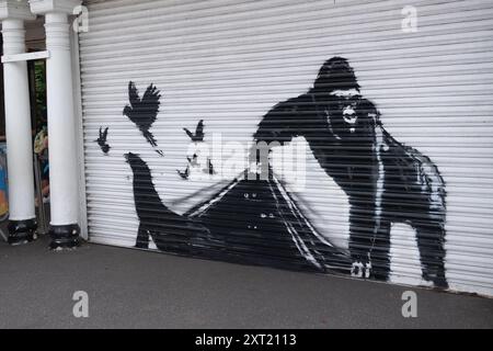 London, Großbritannien. August 2024. Die Leute machen Fotos von dem neunten neuen Tiergemälde des Street-Künstlers Banksy, das einen Gorilla zeigt, der die Fensterläden hebt, um Robben, Vögel und Schmetterlinge am Eingang des Londoner Zoos hervorzubringen. Quelle: Justin Ng/Alamy Live News Stockfoto