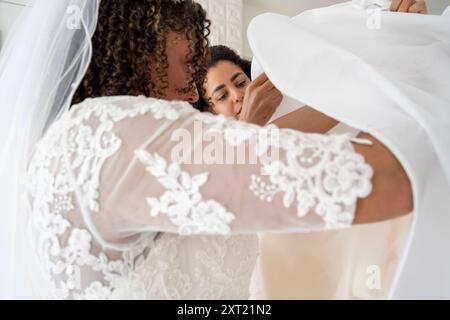 Braut in einem Spitzenkleid und bekommt Hilfe mit ihrem Schleier von einer anderen Frau drinnen. Panc05918 Copyright: XConnectxImagesx Stockfoto