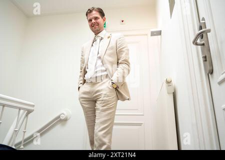Ein lächelnder Mann in einem beigefarbenen Anzug, der selbstbewusst in einem weißen Flur steht, mit der Hand in der Tasche. Panc05920 Copyright: XConnectxImagesx Stockfoto