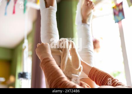 Kind, das auf dem Rücken liegt und einen gefüllten Häschen hält, mit erhobenen Füßen und gestreiften Socken. Panc06146 Copyright: XConnectxImagesx Stockfoto