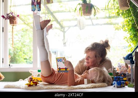 Mutter kümmert sich um ihr verletzte Kind mit Gips an den Beinen. Im Bett liegen und ihnen vorlesen. Panc06164 Copyright: XConnectxImagesx Stockfoto