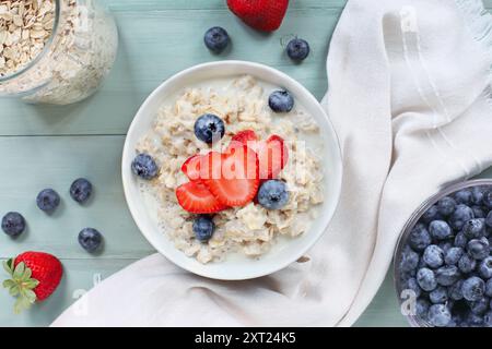 Hausgemachte heiße Schüssel mit cremigem Vollkornhaferbrei mit frischen Erdbeeren und Heidelbeeren. Bild aus der Tischansicht aufgenommen. Stockfoto