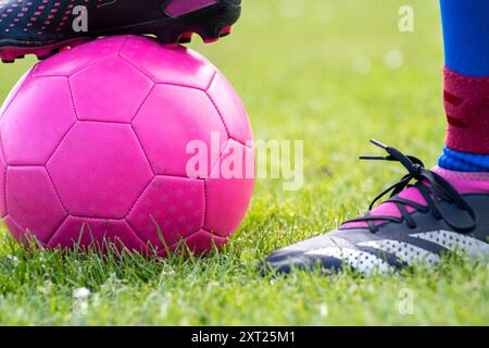 Nahaufnahme eines rosafarbenen Fußballballs mit dem Fuß eines Spielers oben und einem anderen daneben auf einem Rasenfeld. Panc06295 Copyright: XConnectxImagesx Stockfoto
