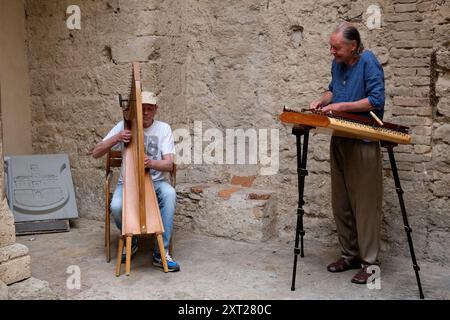 San Gimignano in der Toskana, Italien, Musiker spielen historische Instrumente Harfe und Xylofon im Innenhof des Palazzo del Popolo Stockfoto