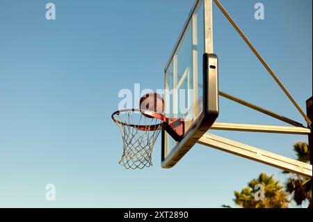 Basketballkorb im Freien mit einem Ball, der durch das Netz gegen einen klaren blauen Himmel geht. Bola02892 Copyright: XConnectxImagesx Stockfoto