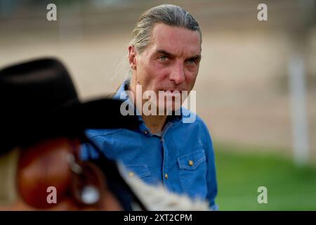 Mann mit grauen langen Haaren und blauem Hemd, der einen intensiven Blick hinter eine verschwommene Figur in einem Cowboyhut wirft. Bola03089 Copyright: XConnectxImagesx RECORD Stockfoto