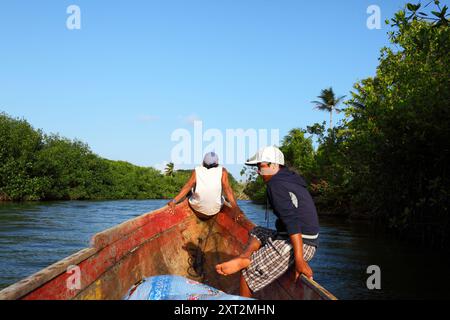 Kuna-einheimische Jungen sitzen auf Bug eines traditionellen Holzkanus auf dem Rio Grande de Carti, Comarca de San Blas, Panama Stockfoto