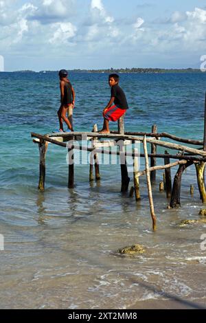 Kuna-Jungs auf rustikalem Steg aus Holzstangen, Stäben und Balken, Carti Sugtup Island, San Blas Inseln, Panama Stockfoto