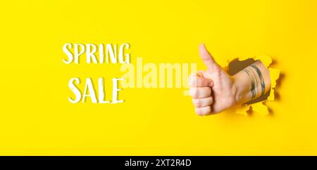 Eine Hand, die einen Daumen nach oben gibt, mit den Worten Spring Sale darunter. Das Bild hat eine helle und positive Stimmung, die ein Gefühl der Begeisterung und vermittelt Stockfoto