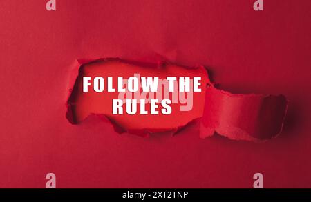 Ein roter Hintergrund mit einem roten Loch und die Wörter folgen den Regeln, die darunter geschrieben sind Stockfoto