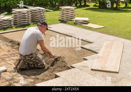 Ein Arbeiter bereitet den Schleif und Zement vor, um den Boden der Betonplatten zu platzieren. Bodenarbeiten und Außenpflaster. Stockfoto