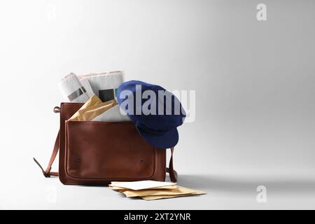 Braune Brieftasche, Briefumschläge, Zeitungen und Hut auf grauem Hintergrund. Leerzeichen für Text Stockfoto