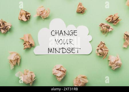 Ein Stapel zerknitterten Papiers mit den Worten „Change Your Mindset“ darauf steht. Das Papier ist auf dem Bild verstreut, wobei einige Papierstücke o platziert sind Stockfoto