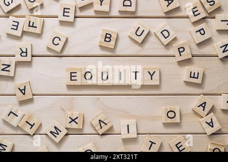 Ein Holzbrett mit einem Gewirr von Buchstaben, die darüber verstreut sind. In den Buchstaben steht das Wort "Equity" in der Mitte des Bretts. Die Szene ist eine von Confusi Stockfoto