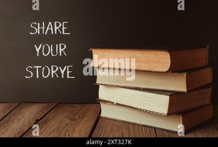 Ein Stapel Bücher mit den Worten erzählen Ihre Geschichte, die auf einer Tafel hinter ihnen geschrieben ist Stockfoto