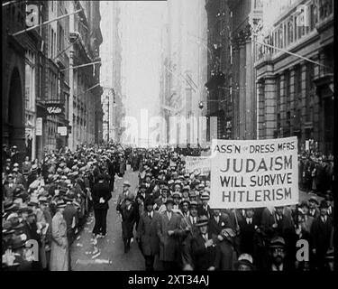 Amerikanische Antifaschisten marschieren und halten Schilder, 1933. Bekleidungsarbeiter in New York protestieren gegen die Verfolgung von Juden durch die Nazis: „Association of Dress Manufacturers – Judaism will Survival Hitlerism“. Überall auf der Welt, wo es große jüdische Gemeinden gab, gab es Demonstrationen, Proteste, und nirgendwo wurden Stimmen höher als in den Vereinigten Staaten erhoben. Aber nur Worte werfen keinen Tyrannen um. Aus „Time to Remember – The Time of the Monster“, 1933 (Reel 4); ein Dokumentarfilm über die Ereignisse von 1933, Rise of Roosevelt und Hitler. Stockfoto