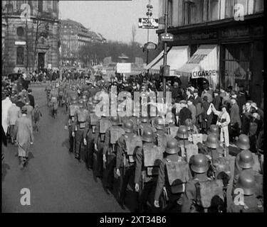 Die Menge beobachtet deutsche Soldaten, die eine Straße weg von der Kamera marschieren, 1930er Jahre Aus "Time to Remember - the Powers that WHO WE", 1930er Jahre (Walze 3); ein Dokumentarfilm über verschiedene wichtige Figuren der 1930er Jahre Stockfoto